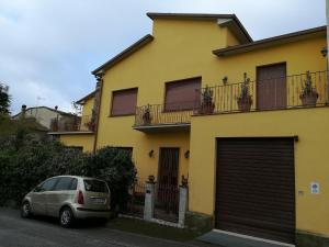 un coche aparcado frente a una casa amarilla en la Chiave di Giano en Foiano della Chiana