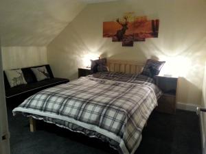 a bedroom with a bed with a plaid blanket at Combie Home in Oban