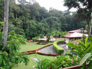 a garden with a pond and a building and trees at El Tucano Resort & Thermal Spa in Quesada