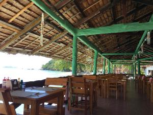 a restaurant with wooden tables and chairs and a body of water at Koh Ngai Resort in Ko Ngai
