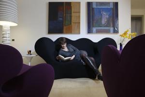 a woman sitting on a couch reading a book at Elite Hotel & Spa in Mestre