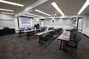ニューブランズウィックにあるRutgers University Inn and Conference Centerのテーブルと椅子、プロジェクションスクリーン付きの教室