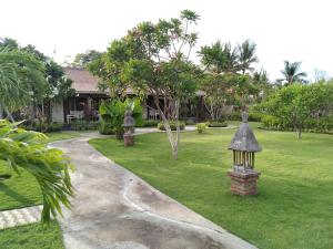 a house with a garden with a bird feeder in the grass at Krisna Homestay in Pemuteran