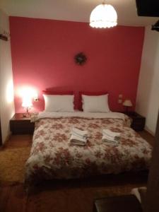 - une chambre avec un grand lit et un mur rouge dans l'établissement Αrchontiko Tis Marios, à Portariá
