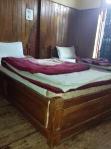 two twin beds in a room with wooden walls at Vamoose Buddha Hotel Tawang in Tawang