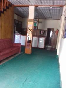 a living room with a red couch and green carpet at Vamoose Buddha Hotel Tawang in Tawang