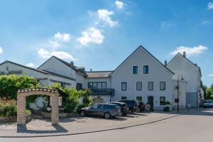 ein großes weißes Gebäude mit Autos auf einem Parkplatz in der Unterkunft Wein Erlebnis Hotel Maimühle in Perl