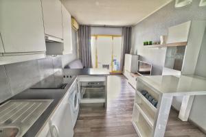 uma cozinha com electrodomésticos brancos e pisos em madeira em Apartment hotel Luxe climatisé vue mer magnifique étage 11 em Villeneuve-Loubet