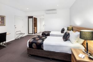 Best Western Plus Ballarat Suites في بالارات: غرفة فندقية بسريرين ومكتب