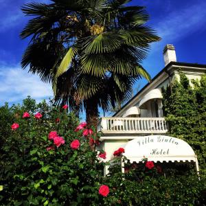 una palmera frente a un edificio con rosas en Hotel Villa Giulia en Tortona