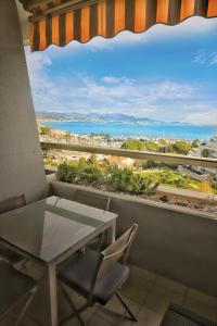 a balcony with a table and chairs and a view of the ocean at Vue Mer T2 Climatisé Marina Baie des Anges, étage 11, plages à 100 m in Villeneuve-Loubet