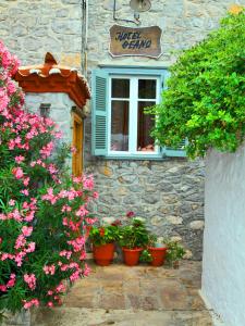a stone building with flowers in front of a window at Theano Guesthouse in Hydra