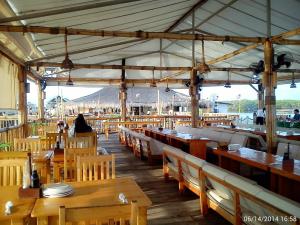 a restaurant with wooden tables and chairs and a person at Haus of Emerald - Astana by Ollie in Mactan