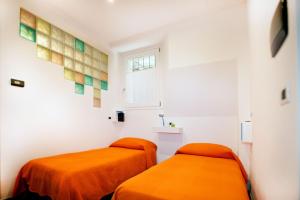 two orange beds in a white room with a window at Appartamento Melissa in Santa Maria Maggiore