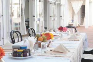 Savista Retreat في جايبور: طاولة طويلة عليها قماش الطاولة البيضاء والفواكه