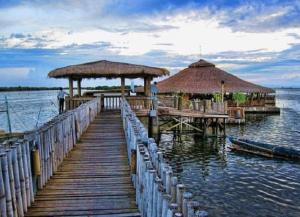 a wooden dock with two umbrellas and a pier with a pier at Haus of Emerald - Astana by Ollie in Mactan