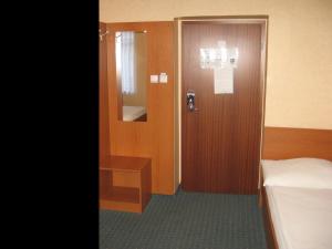 a room with a door and a bed and a mirror at Hotel Arnold in Tata