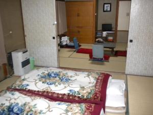 a room with a bed with a floral pattern on it at Mimatsuso Ryokan in Asahikawa