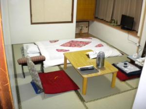 Cette petite chambre comprend un lit et une table. dans l'établissement Mimatsuso Ryokan, à Asahikawa