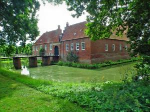 an old brick building with a bridge over a river at Haus Swantje in Hinte