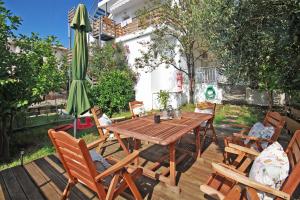 a wooden table and chairs with a green umbrella at STUDIOS MOUSE HOUSE in Neos Marmaras
