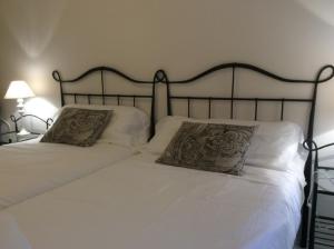 um quarto com 2 camas com lençóis brancos e almofadas em Apartamento Oteiza em San Sebastián
