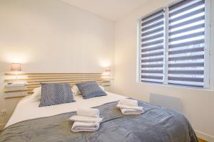 a bedroom with a large bed with towels on it at Port de Caen Haut de Gamme in Caen