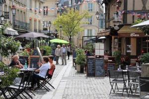 un grupo de personas sentadas en mesas en una calle de la ciudad en Port de Caen Haut de Gamme, en Caen