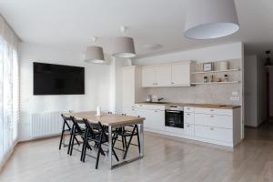 cocina con armarios blancos, mesa y sillas en Auredius Deluxe Apartment en Kranjska Gora