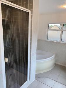 Das Bad ist mit einer Badewanne und einer Glasdusche ausgestattet. in der Unterkunft Lyndricks House in Ascot