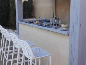 eine Reihe weißer Stühle und eine Theke mit Weingläsern in der Unterkunft Villa with private pool and lake view in Narbonne