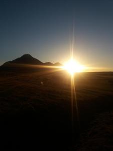 a sunset in the desert with a mountain in the background at Midhop guesthouse in Þingeyrar
