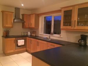 a kitchen with wooden cabinets and a black counter top at ArdMullen Townhouse X Davitt's Guesthouse & Restaurant Kenmare in Kenmare