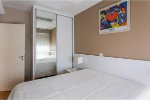 una camera da letto con un letto bianco e uno specchio di Duplex NYC Berrini 2 dormitórios - ao lado do WTC a San Paolo Altre 16 foto