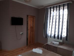 a room with two beds and a television and a window at Kazbegian Host in Kazbegi