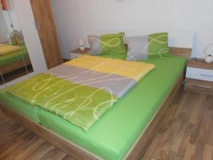 a bed with a green and yellow comforter at Ferienwohnung Michaela in Flattach