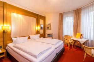 a hotel room with a large bed and a table at CityHotel Kempten in Kempten
