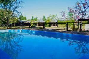 a swimming pool with a fence and a house at La Argentina Complejo in Villa Ciudad de América