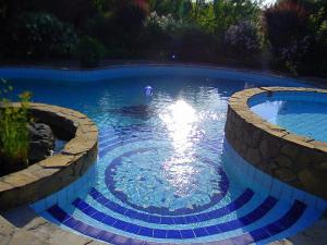 una gran piscina con azulejos azules en un patio en Rosehill Cottage, en Orbányosfa