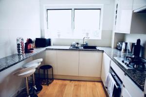 ロンドンにあるKing's Cross 2BR Modern Flat Central Londonの白いキャビネット、シンク、窓付きのキッチン