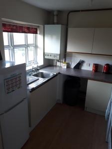 a kitchen with white cabinets and a sink at Marvellous Meridian Maisonette in Ifield