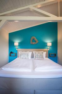 ein großes weißes Bett mit einer Wand mit blauen Akzenten in der Unterkunft Hotel kleine Auszeit - Adults Only in Sankt Peter-Ording