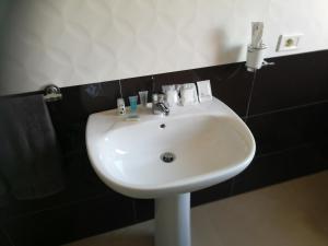 a white sink in a bathroom with black tiles at Bed & Breakfast Hollywood in Villarosa