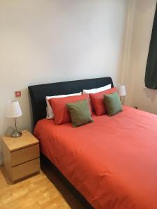 a bedroom with a bed with red sheets and green pillows at Stylish City Centre Apartment in Cardiff