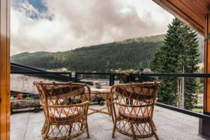 dwa krzesła i stół na balkonie z widokiem w obiekcie CENTRAL WOODEN CHALET WITH FOREST VIEW w Madonna di Campiglio