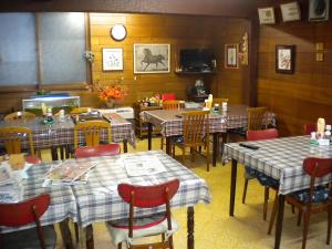 a restaurant dining room with tables and chairs and a clock at Mimatsuso Ryokan in Asahikawa