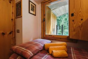 Bett in einem Zimmer mit einem großen Fenster in der Unterkunft CENTRAL WOODEN CHALET WITH FOREST VIEW in Madonna di Campiglio