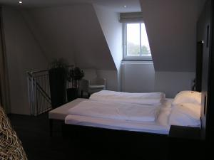 
a white bed sitting in a bedroom next to a window at Hotel zur Promenade in Donauwörth
