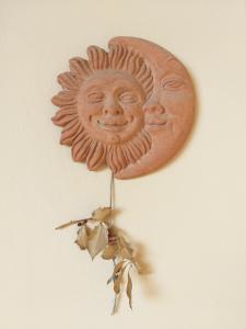 una decoración solar de madera en una pared con hojas en Casa SoleLuna, en Siena