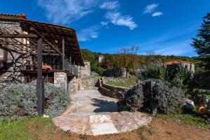 una casa de piedra con un camino que conduce a un edificio en Green's House en Poliána